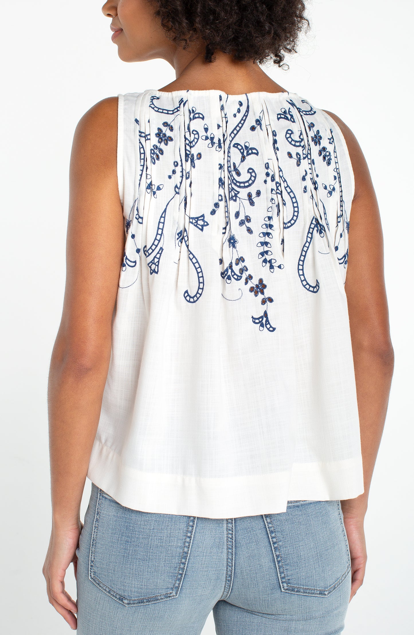 Sleeveless Boat Neck Woven Top W/ Pintucks in white with blue floral embroidery on back