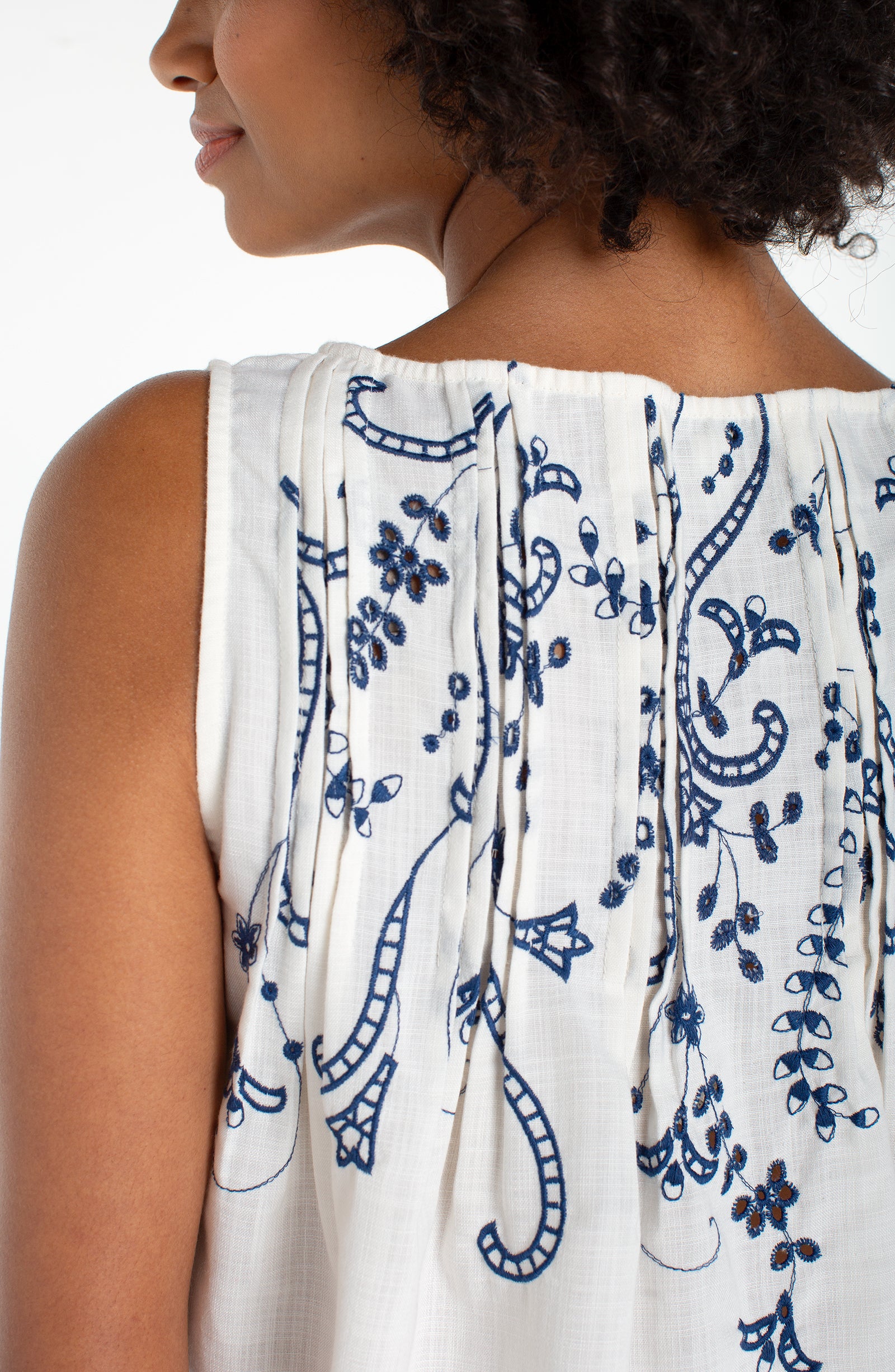 Sleeveless Boat Neck Woven Top W/ Pintucks in white with blue floral embroidered pintuck details