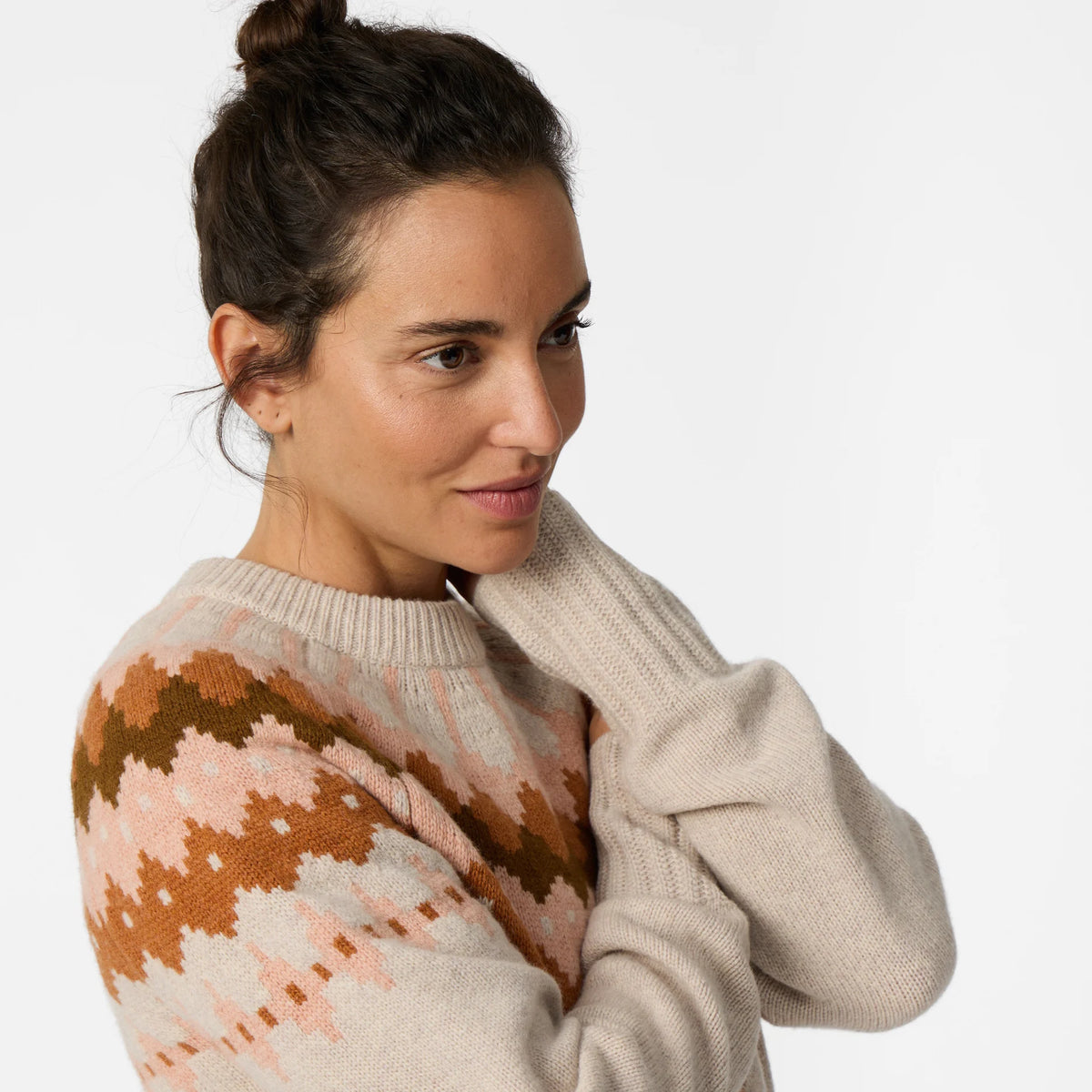 Woman wearing a cream and rust patterned sweater against a light background