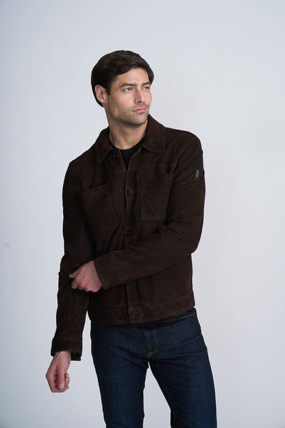 Man wearing a dark brown jacket and jeans against a light background