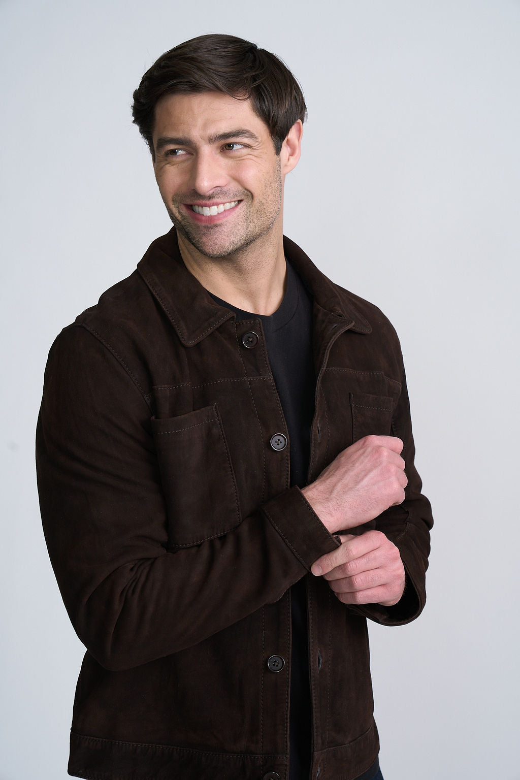 Smiling man wearing a dark brown jacket over a black shirt